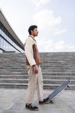 Afro kaykaycı sokakta kaykay üzerine bastı