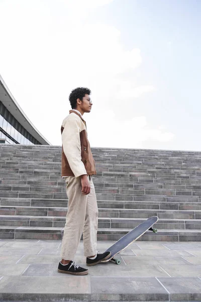 Afro kaykaycı sokakta kaykay üzerine bastı