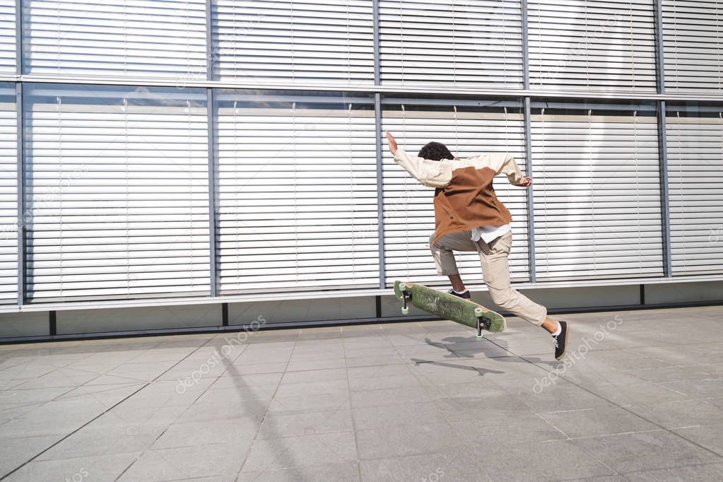 Skateboarder in action near windows with shutters