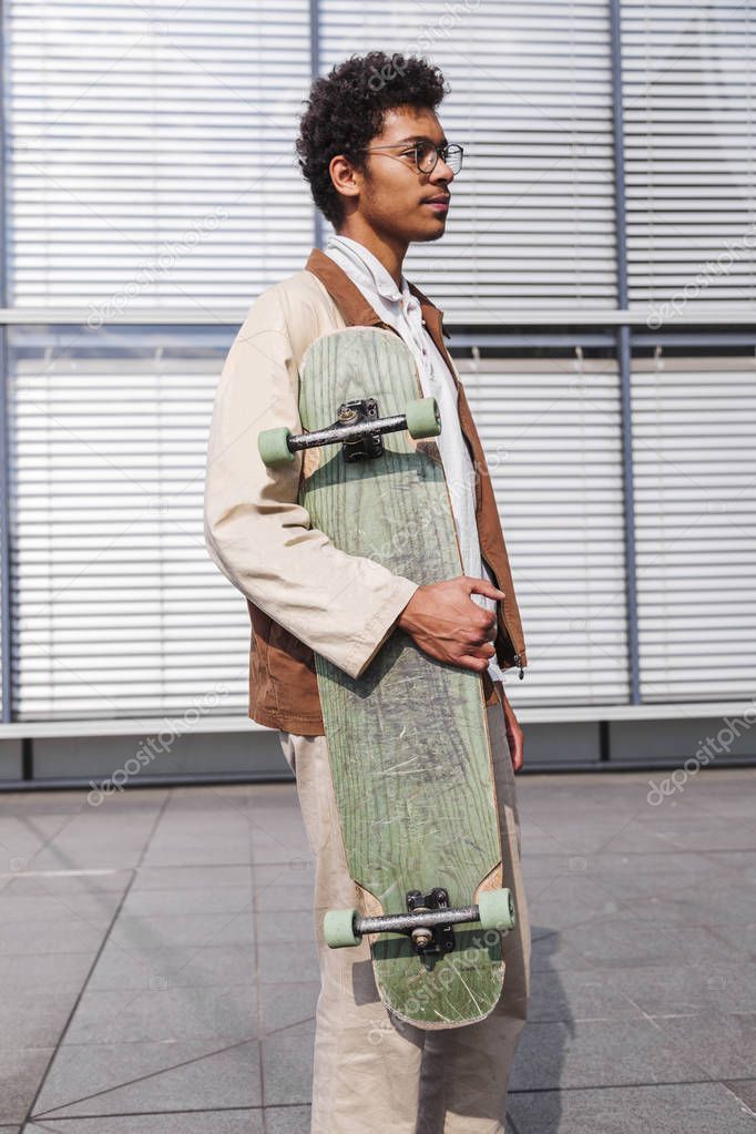 Skateboarder stands with his skateboard in city