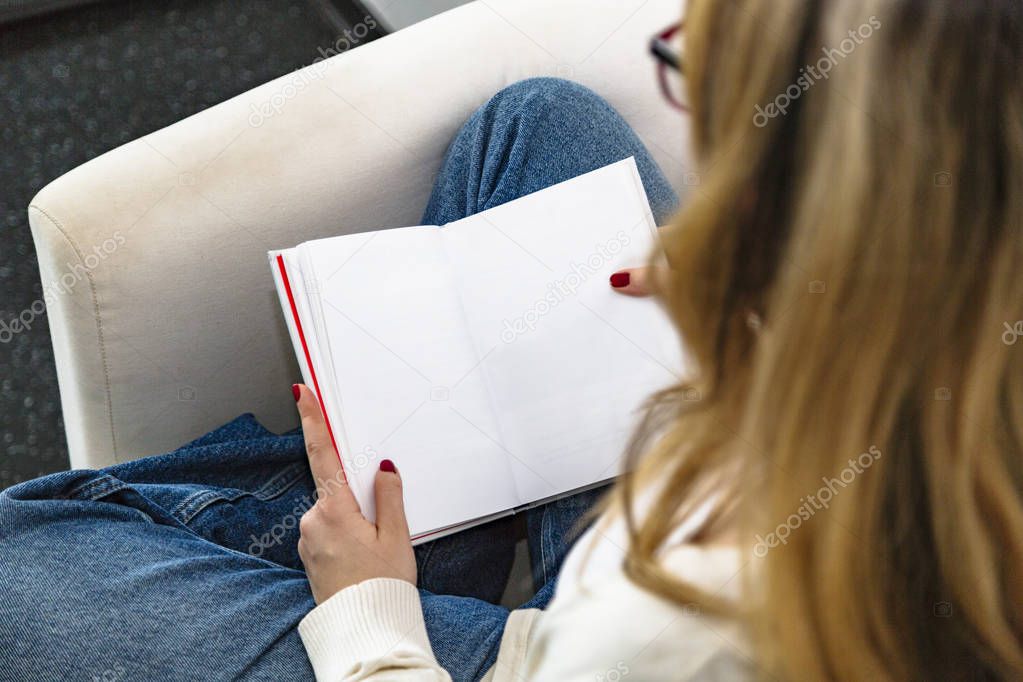 Top view of reading blonde girl sitting in chair