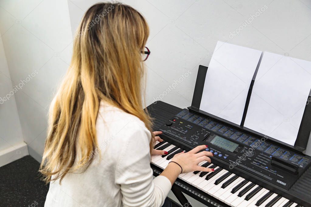 Young girl plays song on notes on synthesizer
