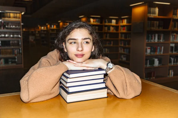 Jeune femme tenant une pile de livres à la bibliothèque — Photo