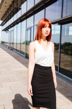 Genç iş kadını modern bina boyunca yürüyor.