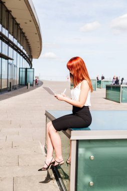 Kız sokakta oturan formlara bir şeyler yazıyor.