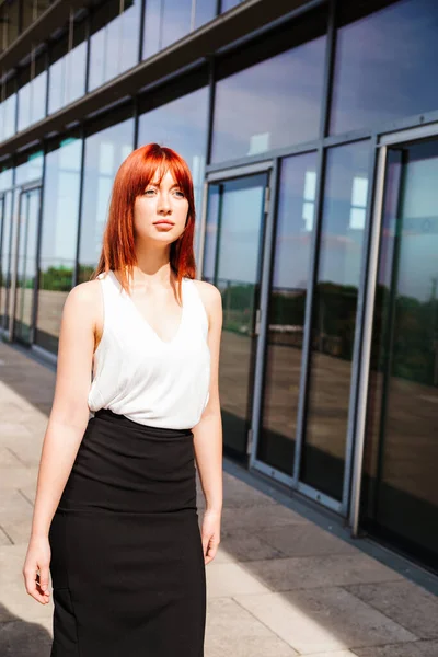 Young business woman walks along modern building