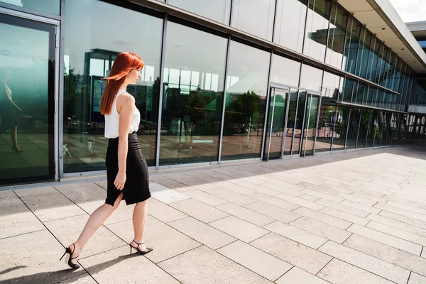 Jovem mulher de negócios caminha ao longo do edifício moderno — Fotografia de Stock