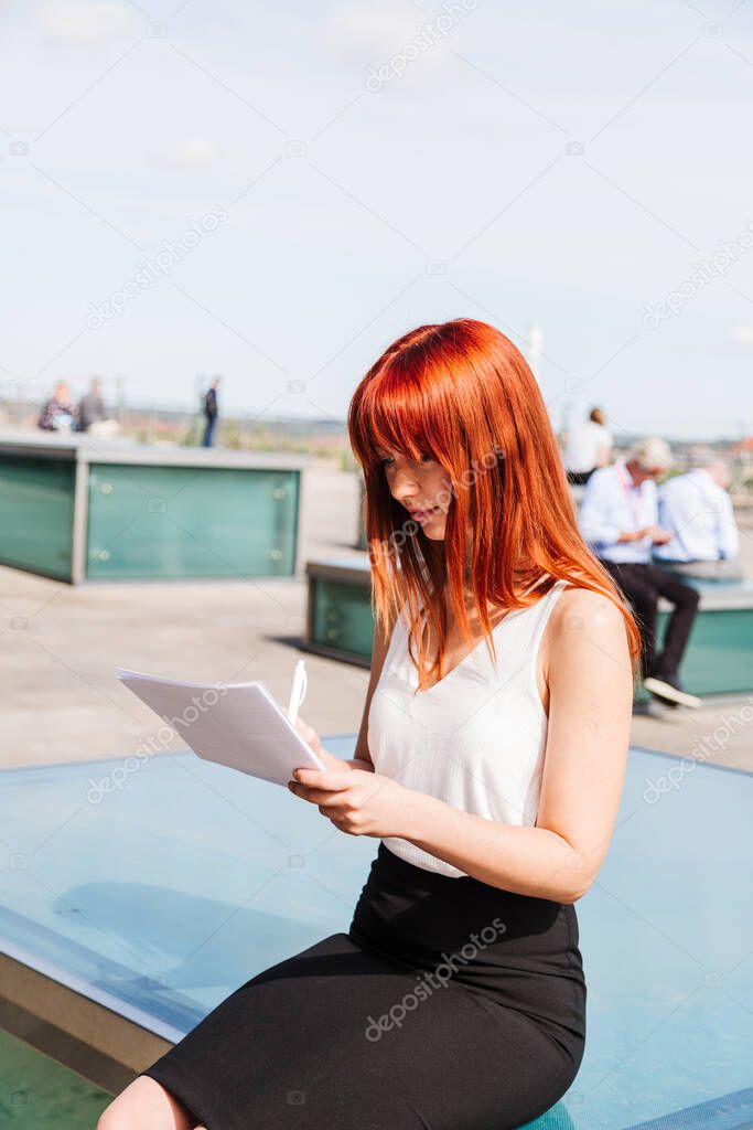 Girl writes something on forms sitting on street
