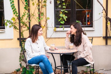 İki genç kadın kafede konuşuyor ve kahve içiyor.