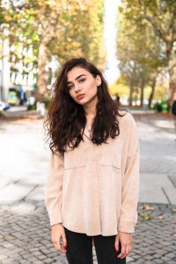 Güzel esmer genç bir kadın sokakta yürüyor.