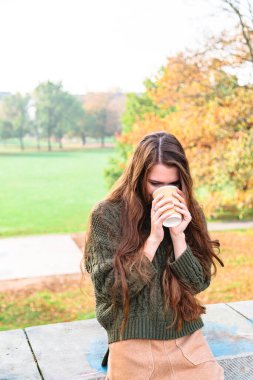 Doğadaki genç kız, kağıt bardaktan kahve içer.