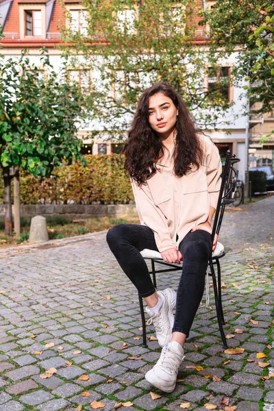 Menina sentada na cadeira na rua no fundo de madeira — Fotografia de Stock