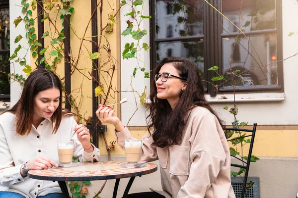 Meninas gostam de cappuccino na mesa de café na rua — Fotografia de Stock