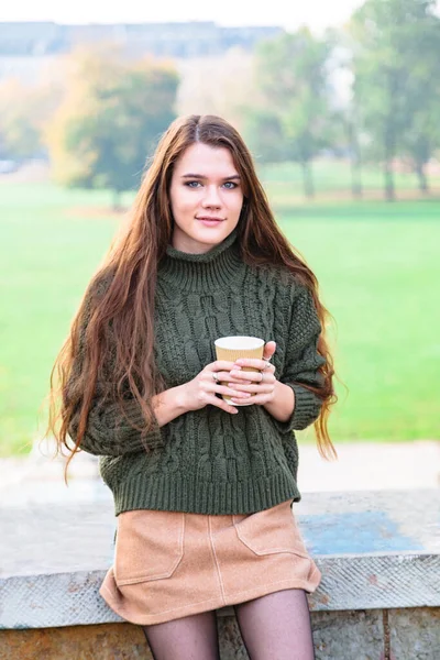 Chica disfruta del olor de café sentado en el parque de otoño — Foto de Stock