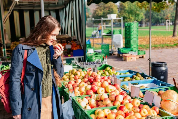 Girl buys fruit and sniffs apple at street market — Stock Photo, Image
