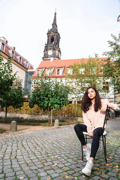 Menina sentada na cadeira na rua no fundo de madeira — Fotografia de Stock