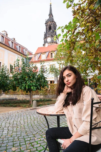 Menina sentada na cadeira na rua no fundo de madeira — Fotografia de Stock