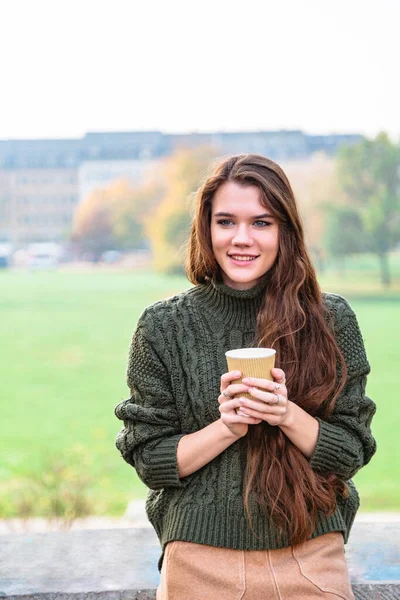 Menina sorridente com xícara de café senta-se na cerca — Fotografia de Stock