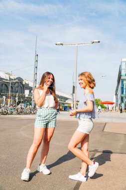 # Yazlık elbiseli iki gülümseyen kız ayakta dikiliyor #