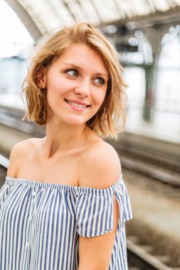 Sarışın kadın tren istasyonunda tren bekliyor.