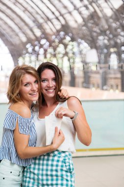 Tren biletlerini tutan ve sarılan genç kadınlar.