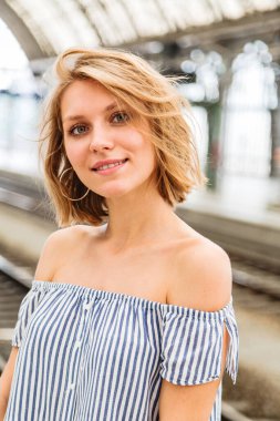 Tren istasyonunda sarışın bir kızın yakın plan portresi.