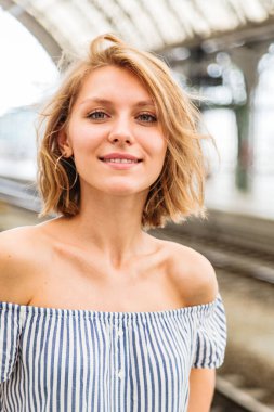 Tren istasyonunda sarışın bir kızın yakın plan portresi.