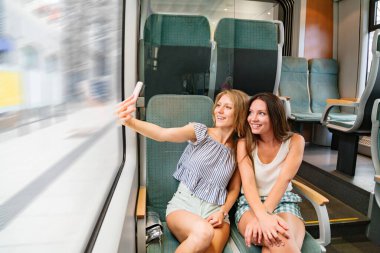 Trende selfie çeken iki kız arkadaş.