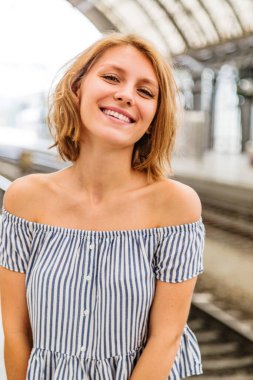 Sarışın kadın tren istasyonunda tren bekliyor.