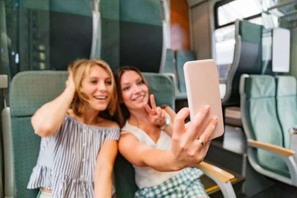 Trendeki kızlar oynaşıp fotoğraf çekiyorlar.