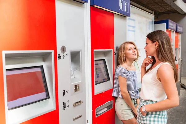 Namoradas escolhendo bilhetes na tela de uma máquina de venda automática — Fotografia de Stock