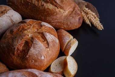 Fırın ekmek üreticileri - altın rustik huysuz somun ekmek ve siyah kara tahta zemin üzerine buns. 