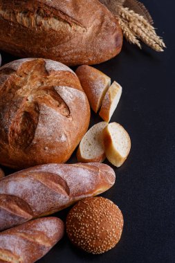 Fırın ekmek üreticileri - altın rustik huysuz somun ekmek ve siyah kara tahta zemin üzerine buns. 