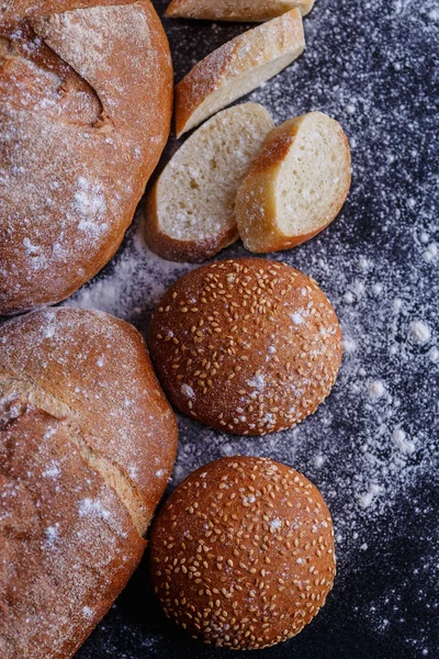 Bäckerei - goldene, rustikale, krustige Brotlaibe und Brötchen auf schwarzem Blech — Stockfoto