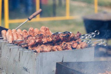 Adam terbiye edilmiş şiş kebap pişiriyor, kuzu eti metal şişte ızgara yapıyor. Beyaz duman, yaklaş. Shish kebabı ızgarada kızartıyordu. Barbekü partisi. Yakın plan..