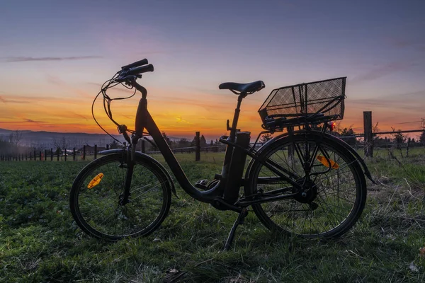 Bahar akşam ışık yeşil çayır üzerinde gün batımı ile siyah Elektrikli bisiklet