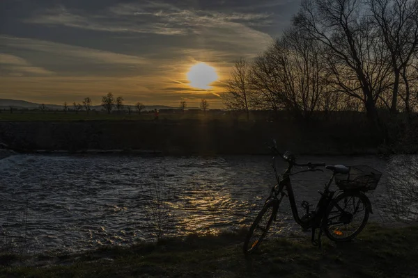 Fekete elektromos kerékpár naplementével a Weir közelében a Malse folyón — Stock Fotó