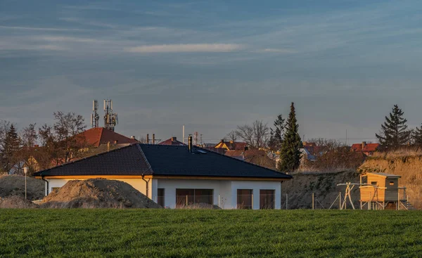 Färg fält och blå himmel i solnedgången tid nära Ceske Budejovice med nya hus — Stockfoto