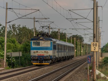 Moravya 'nın güneyindeki hızlı demiryolunda elektrikli mavi motor ve koçlar.
