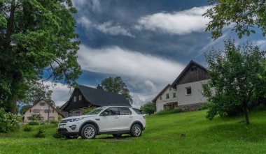 Kırsal kesimdeki beyaz büyük off-road arabası mavi gökyüzü bulutlarında yeşil çayır üzerinde