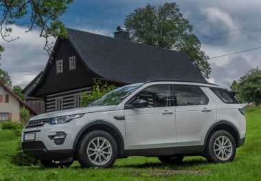 Kırsal kesimdeki beyaz büyük off-road arabası mavi gökyüzü bulutlarında yeşil çayır üzerinde