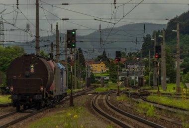 Bulutlu bir yaz gününde kargo treni ve renkli semaforlu Knittelfeld istasyonu