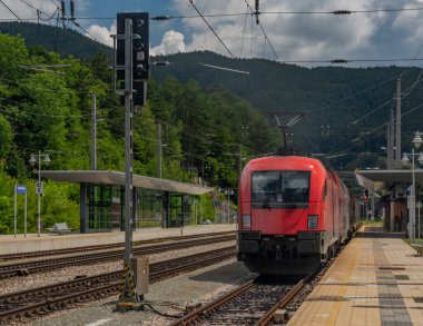 Yaz aylarında bulutlu bir günde kırmızı elektrikli yolcu ünitesi olan Payerbach-Reichenau istasyonu