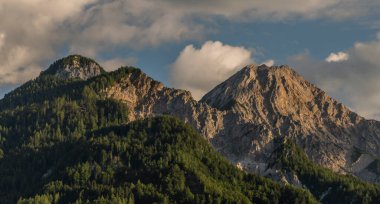 Slovenya ve Avusturya sınırındaki Mittagskogel tepesinin altında bulutlu ve mavi gökyüzü yaz akşamı