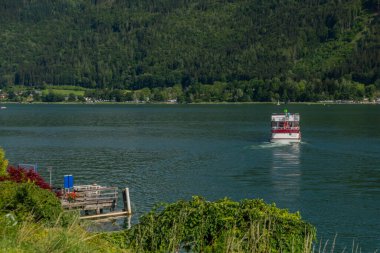 Ossiacher 'daki yolcu gemisi sıcak mavi gökyüzü gününde Villach kasabasının yakınına bakıyor.