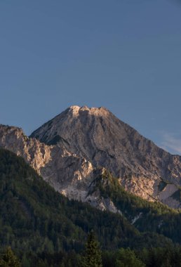 Slovenya ve Avusturya sınırındaki Mittagskogel tepesinin altında bulutlu ve mavi gökyüzü yaz akşamı