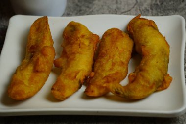 Yakın plan Pisang Goreng veya beyaz tabakta kızarmış Endonezya muzlu böreği. Popüler bir tatlı ya da tatlı.