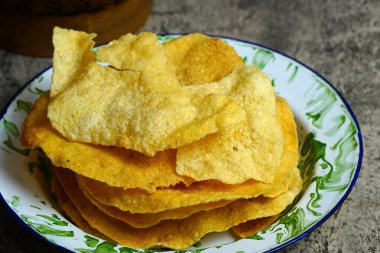 Altın ve çıtır opak ya da eski bir diş minesi tabağında Endonezya Cassava krakeri. Kıtır kıtır kıtır bir kıtır atıştırmalık..