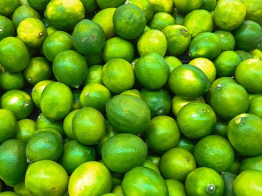 Canlı renklerini, pürüzsüz dokularını ve doğal tazeliklerini vurgulayan taze yeşil limon yığınının tam kare görüntüsü. Yemek, sağlıklı beslenme ve doğal temalar için mükemmel..