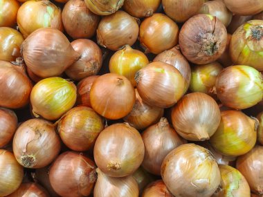 Tam bir çerçeve, büyük bir yığın taze sarı ve kahverengi soğan yakın çekim. Yemek malzemeleri, sağlıklı sebzeler ve pazar üretimi temaları için ideal.